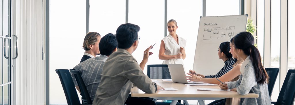 Simulated KDJ Office team collaborates on white board at conference table.